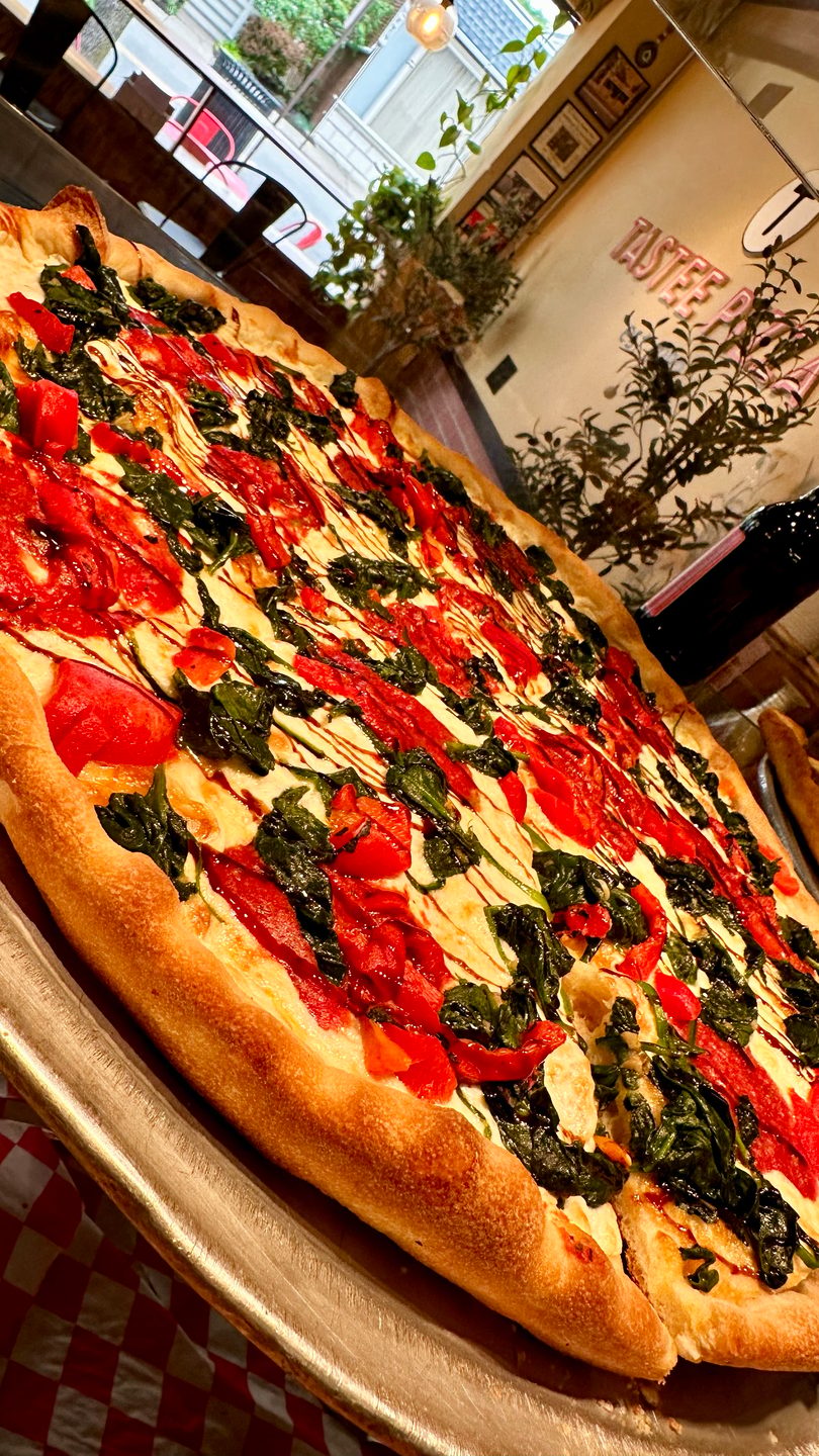 Large pizza with red sauce, white cheese, spinach, and tomatoes, drizzled with balsamic glaze.